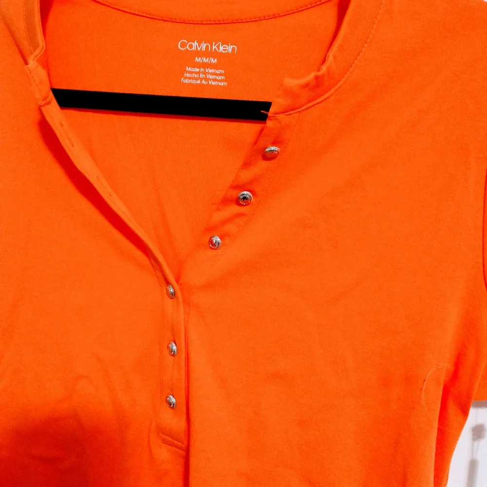 NWOT Calvin Klein orange short sleeve top with half button front detail.  Size